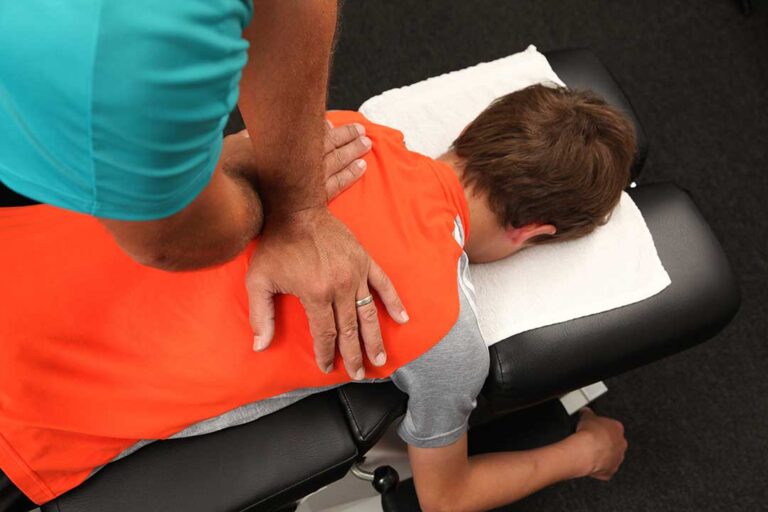 A person gently stretching their neck and shoulders at home, appearing to relax after a body treatment.