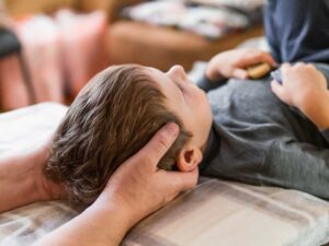 Adult performing guided back exercises beside a treatment table in a bright, calm room.