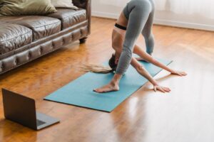 Adult practicing gentle stretches beside a chair with a journal and heating pad nearby
